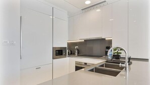 Une cuisine moderne avec des meubles blancs, des appareils en acier inoxydable et un four à micro-ondes encastré.
