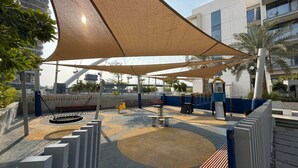 Une aire de jeux avec des balançoires, un toboggan et une structure d’escalade.