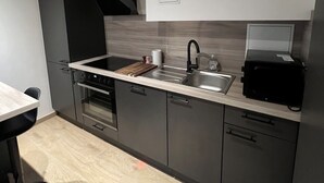 Una cucina moderna con forno integrato, lavello e cappa aspirante nera.