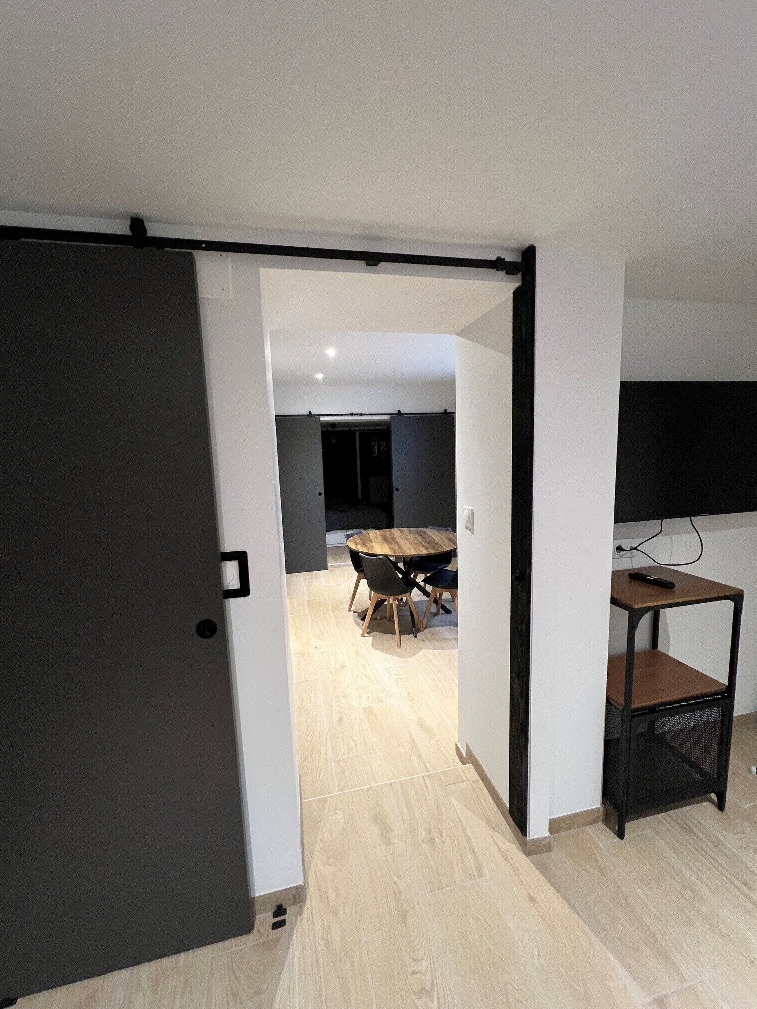 An open door leading to a room with a dining table, chairs, and a television on a stand.