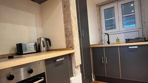 Eine kompakte Küche mit Mikrowelle, Wasserkocher und einem Fenster über der Spüle.
