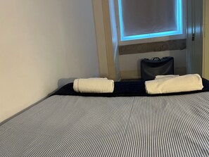 A hotel room with a bed, a window with a view, and a suitcase on the floor. - Arco Augusta Apartment (Lisboa)