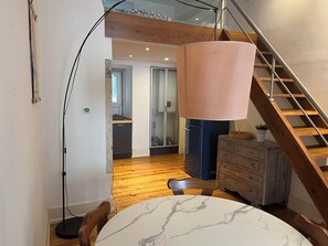 A modern kitchen with a marble countertop, wooden flooring, and a staircase with a wooden railing. - Arco Augusta Apartment (Lisboa)