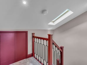 A room with a skylight, a red door, and a staircase with black railings. - London West Retreat 2 by Interhome (London West End)