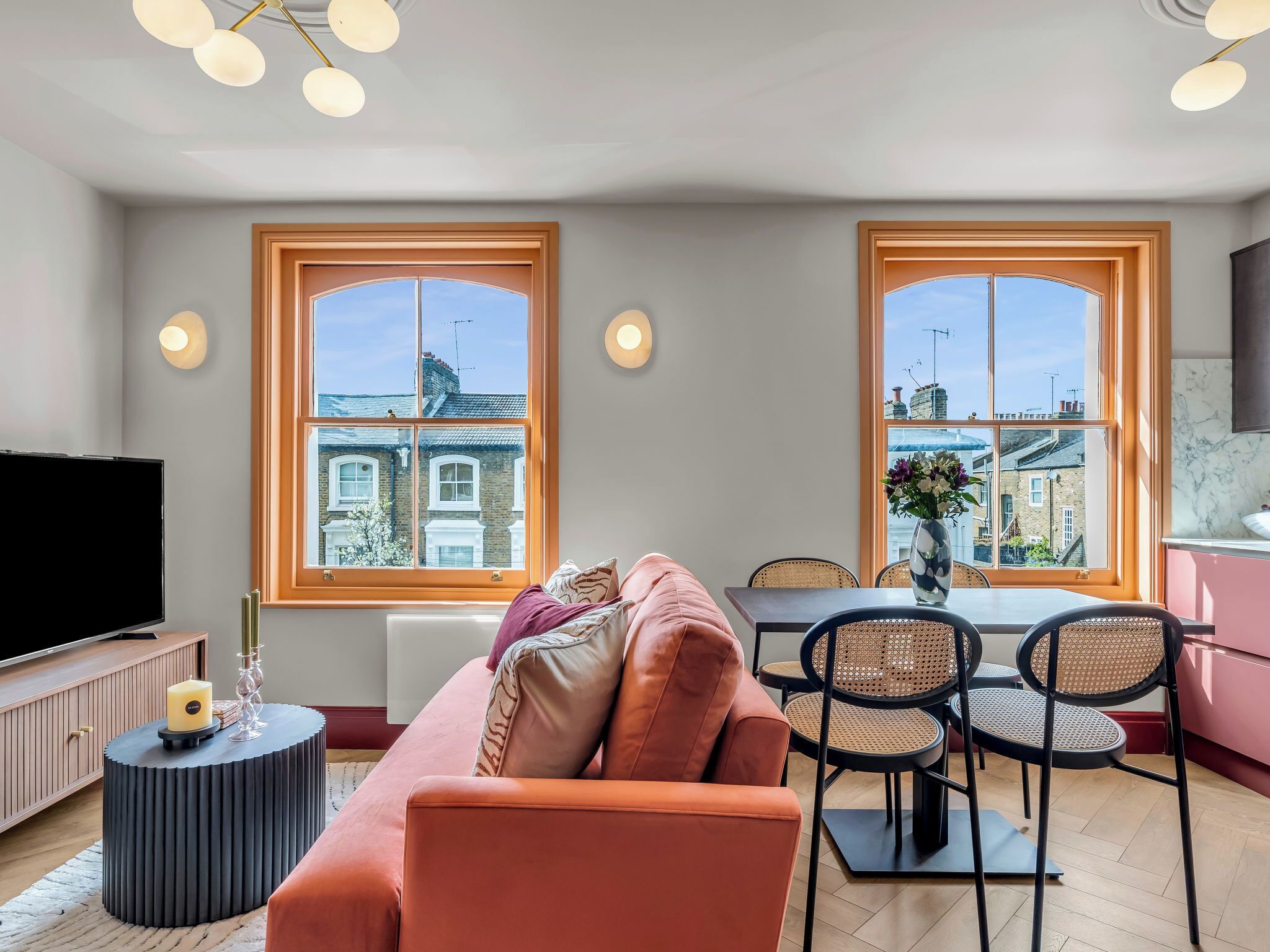 Ein modernes Wohnzimmer mit Sofa, Fernseher und Essbereich mit Stühlen und Tisch.