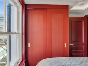 A room with a large window, a bed with a white quilted cover, and two red doors with vertical ridges. - London West Retreat 2 by Interhome (London West End)