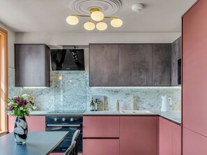 Een moderne keuken met marmeren aanrechtbladen, een inbouwoven en een hanglamp.