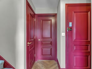 A hallway with two red doors, a light switch, and a wooden floor. - London West Retreat 2 by Interhome (London West End)