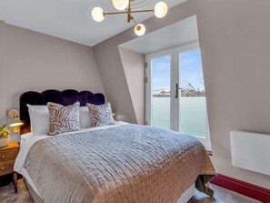 A bedroom with a bed, a nightstand, a lamp, and a window with a view. - London West Retreat 2 by Interhome (London West End)