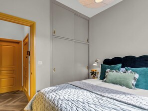 Ein Schlafzimmer mit einem Bett, einem Kleiderschrank, einer Tür und einem Nachttisch mit Lampe.