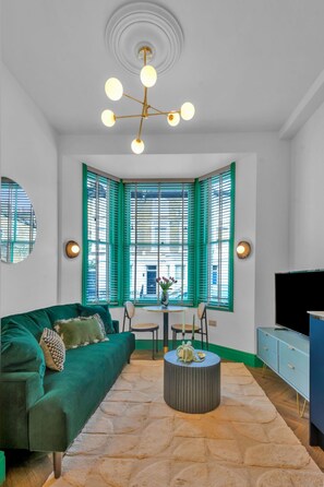 Un salon avec un canapé vert, une table basse ronde et un meuble pour la télévision.