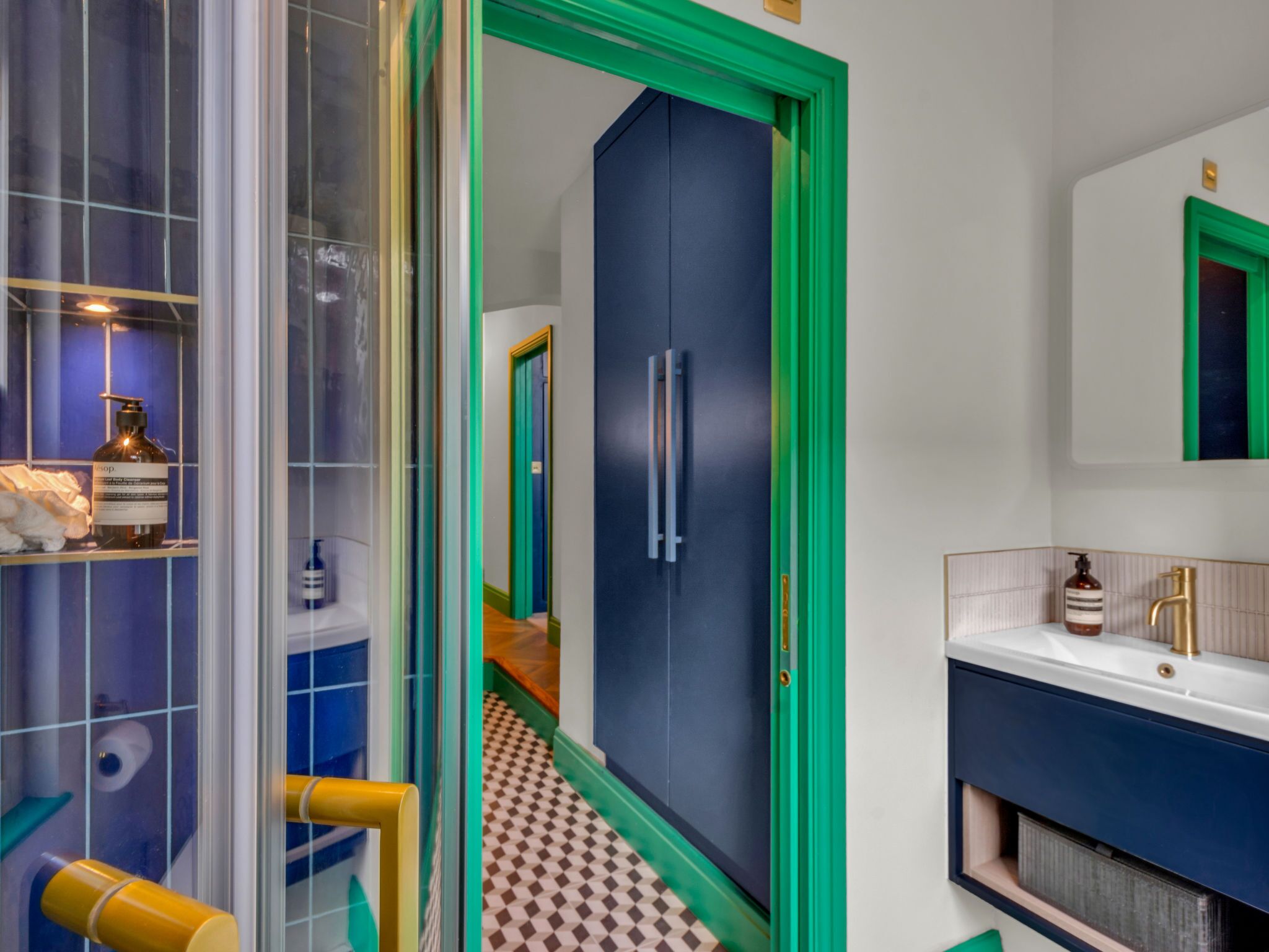 Ein Badezimmer mit einem blauen Schrank, einem Spiegel und einem Waschbecken mit einem goldenen Wasserhahn.