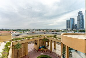 A rooftop terrace with a palm tree, a seating area, and a view of a cityscape with modern buildings.