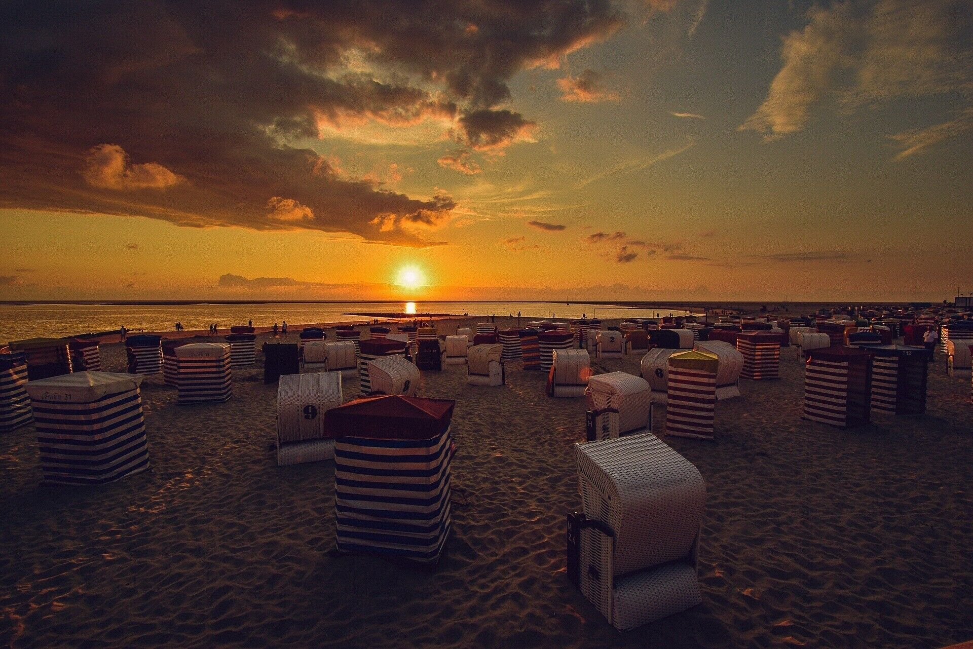 Une plage bordée de rangées de chaises de plage et de parasols à rayures.