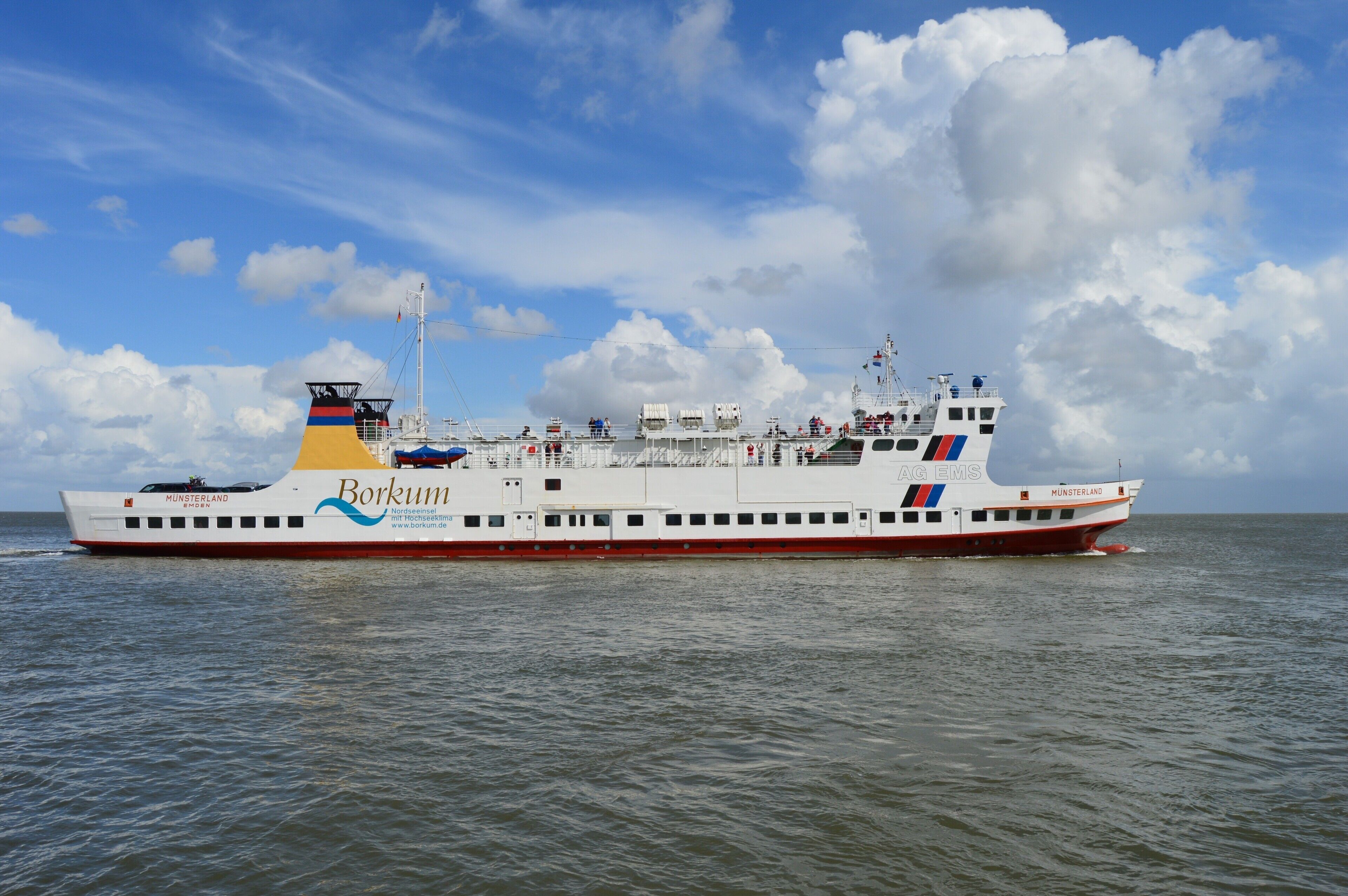 A ferry with the name 'Borkum' and 'Münsterland' on its side, sailing on the water.