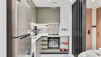 A compact kitchen with a built-in oven, a coffee maker, and a washing machine.