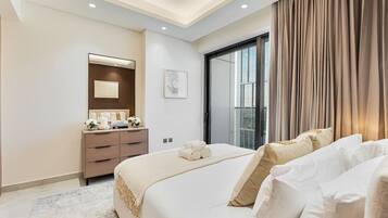 Een moderne hotelkamer met een groot bed, een dressoir, een spiegel en een raam met gordijnen.