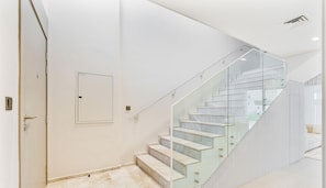 A modern interior with a glass staircase, a door with a handle, and a light switch. - Spacious | 4 Bed Villa | Private Pool | Meydan (Dubai)