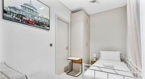 A hotel room with a bed, a bedside table, a nightstand, a mirror, and a framed picture on the wall. - Spacious | 4 Bed Villa | Private Pool | Meydan (Dubai)