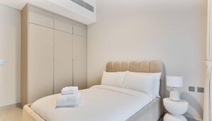 A hotel room with a bed, a wardrobe, a bedside table with a lamp, and a wall socket. - Spacious | 4 Bed Villa | Private Pool | Meydan (Dubai)