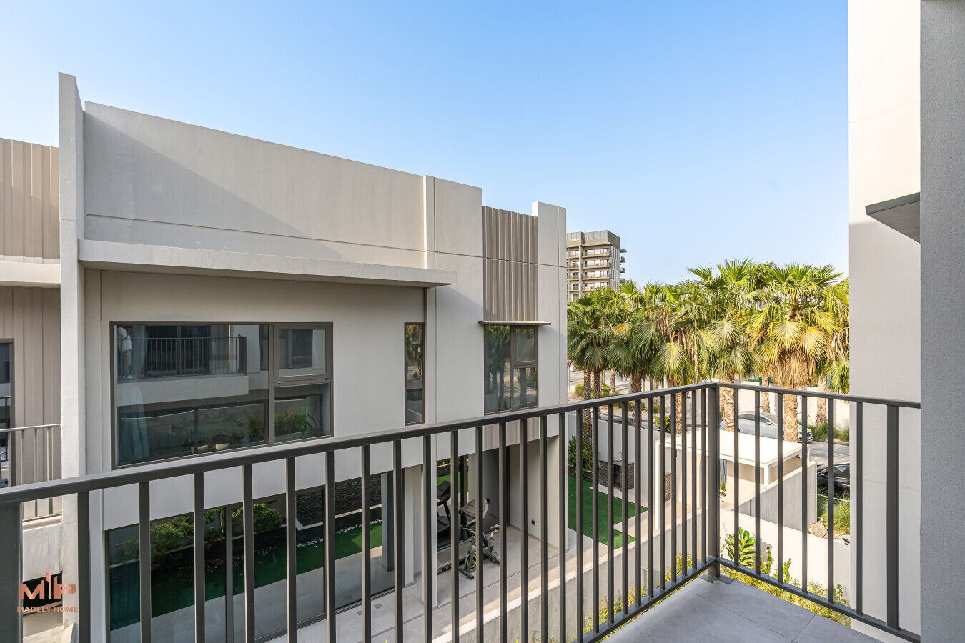 Un bâtiment moderne doté de balcons, de grandes fenêtres et offrant une vue sur des palmiers.