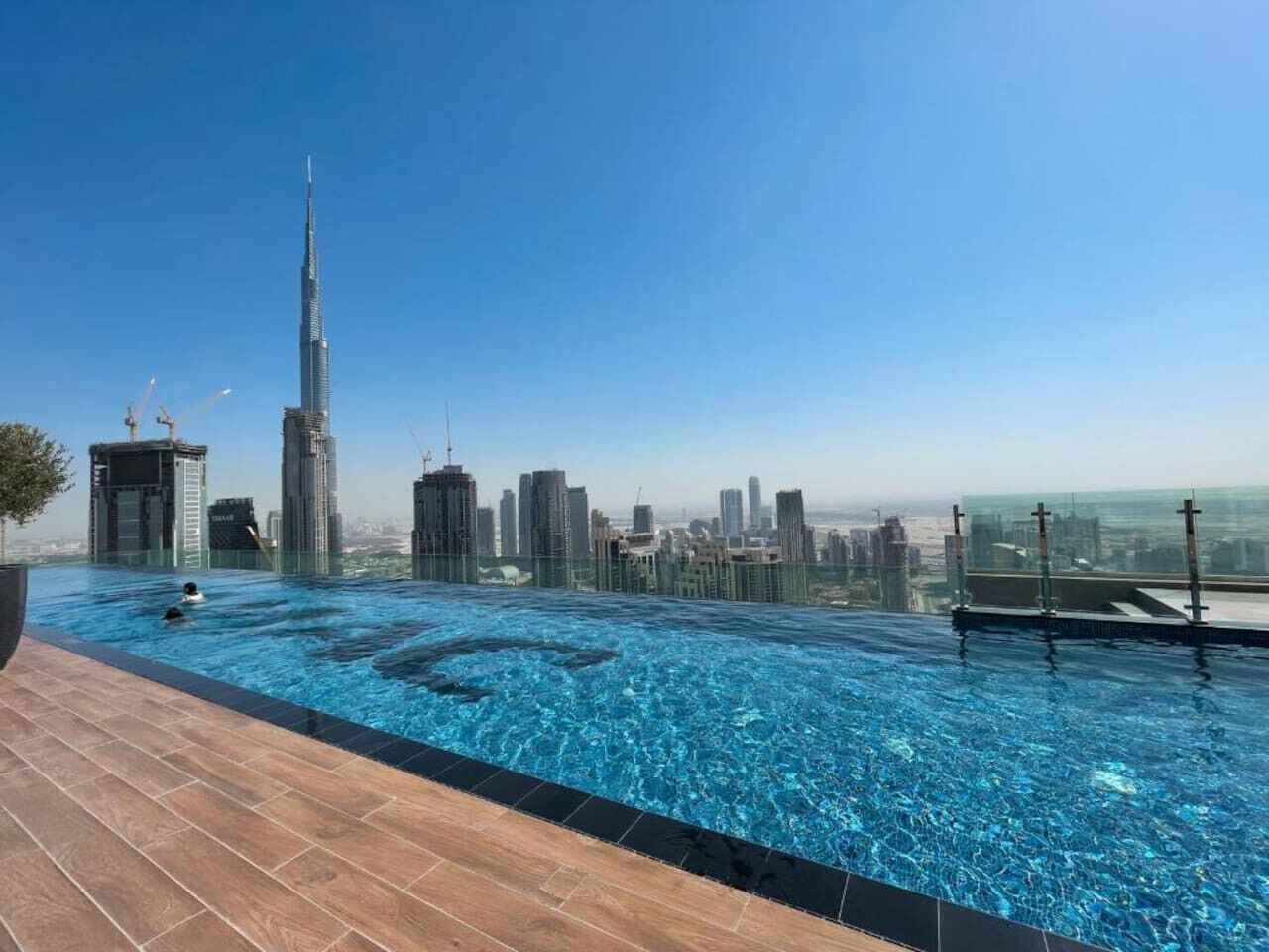 A rooftop infinity pool with a city skyline view, including a prominent skyscraper.