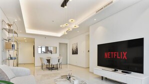 Un saló modern amb un televisor de pantalla plana gran, una zona de menjador i una escala que mena a un pis superior.