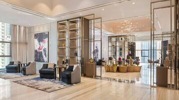 A spacious lobby with modern seating, a large abstract painting, and a glass partition with decorative elements.