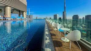 Una piscina al terrat amb vista a l'horitzó urbà, incloent un gratacels destacat.