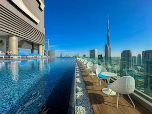 A rooftop pool with a city skyline view, including a prominent skyscraper. - High-Rise | 3 Bed Paramount Midtown | Burj View (Dubai)