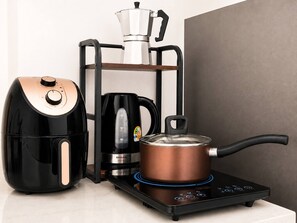 Eine Küche mit Kaffeemaschine, Wasserkocher und Topf auf einem Induktionskochfeld.