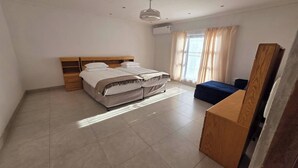 A bedroom with a bed, a desk, a chair, a wardrobe, and a ceiling fan.