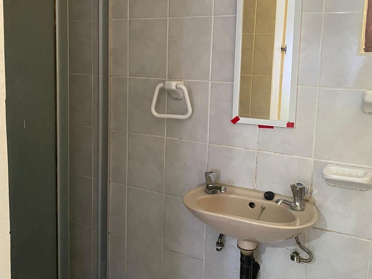 A bathroom with a sink, mirror, and handrail.