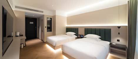 Habitación de hotel con dos camas, un escritorio, una silla, un espejo y una mesita de noche con lámpara.