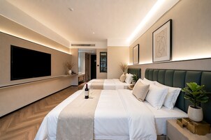 A hotel room with two beds, a flat-screen TV, and a minibar.