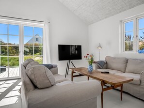 Ein modernes Wohnzimmer mit einer Couch, einem Couchtisch, einem Fernseher und einer Lampe.