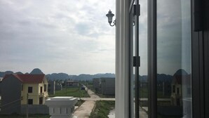 Un balcon donnant sur un quartier résidentiel, une rue et des montagnes lointaines.