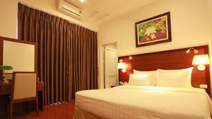 Una habitació d'hotel amb un llit, un escriptori amb una cadira, un quadre a la paret i una porta.