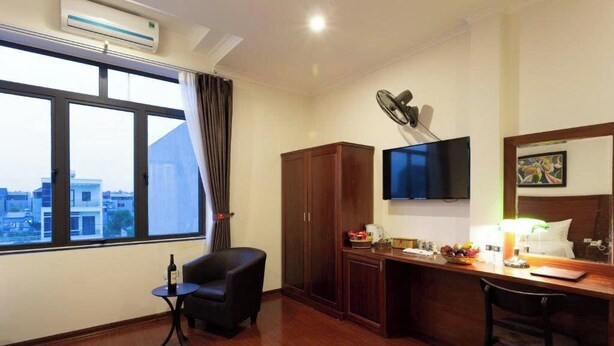 Habitació d'hotel amb una finestra gran, una taula de treball, una televisió de pantalla plana, un armari i una taula petita amb una ampolla.