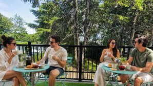 Four people seated at round tables outdoors with green grass and trees in the background. - Chic 2-story condo, a nature retreat for 6 (Québec City)