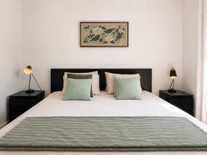 A neatly made bed with two pillows, a green throw blanket, and a framed artwork above it. - Chic 2-story condo, a nature retreat for 6 (Québec City)