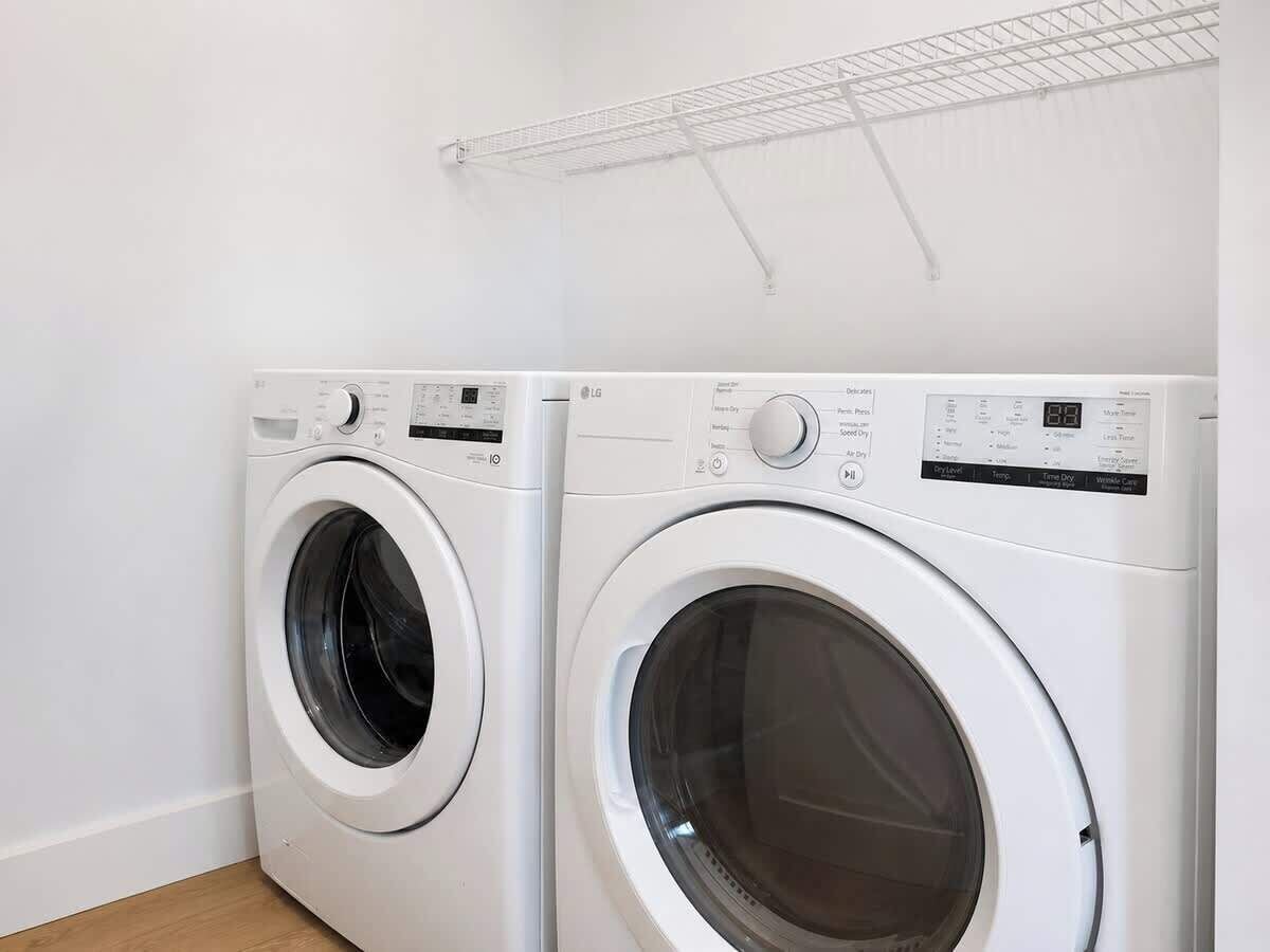 Dos lavadoras de carga frontal blancas en una habitación con pared blanca y suelo de madera.