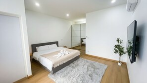 A modern bedroom with a bed, a fluffy rug, a small plant, and a mirror. - Villa Risa (ราไวย์)