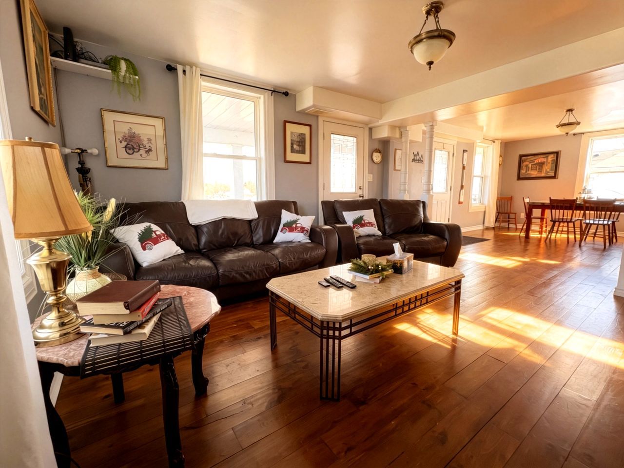 A spacious living room with a brown leather sofa set, a coffee table, and a dining area with a wooden table and chairs.