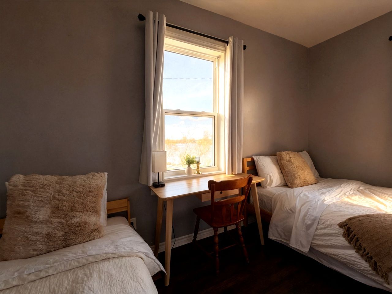 A bedroom with two beds, a desk, and a chair.