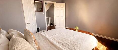 Un dormitorio con una cama grande, una escalera y una puerta que da a otra habitación.