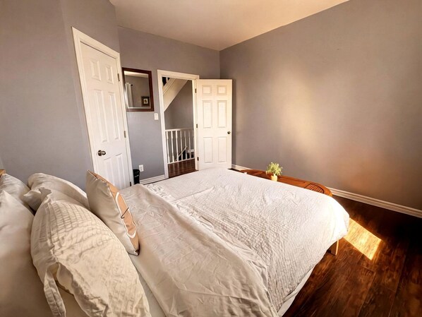 A bedroom with a large bed, a staircase, and a door leading to another room.