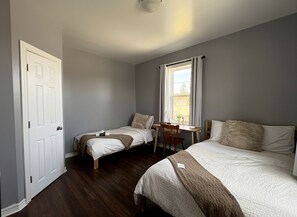 A room with two single beds, a desk, and a chair.