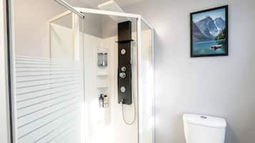 Une salle de bain moderne avec une douche à parois de verre, des toilettes et un tableau représentant un lac de montagne.