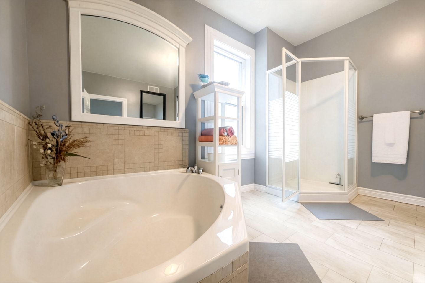 A bathroom with a large bathtub, a glass shower enclosure, and a mirror above the tub.